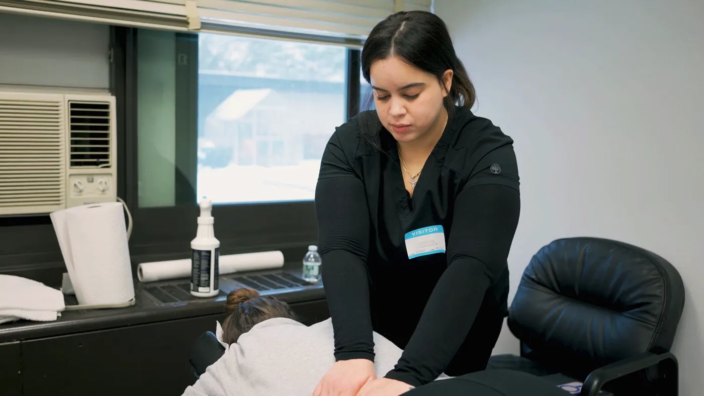 A ReGlow therapist giving a staff member a massage at an on-site event
